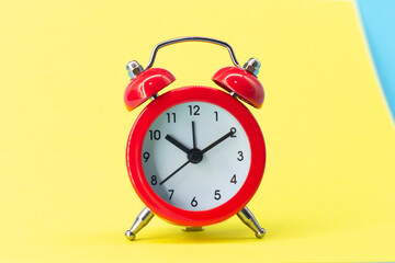 red round analog alarm clock isolated on yellow background. time 10:10. space for text.