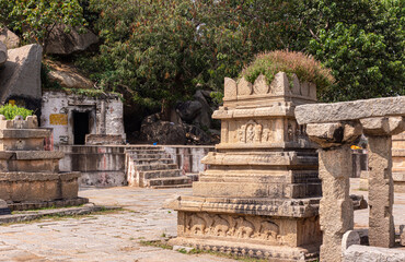 Wall Mural - Anegundi, Karnataka, India - November 9, 2013: Navabrindavana island and temple. Closeup of ruinous brown stone building with green foliage screen in back.