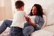 © iordani - young pretty african americam mother with son in bed at morning playing, happy family, lifestyle people concept