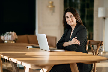 Wall Mural - Economist accountant a woman in a business suit types a message to colleagues. Modern and stylish office. A professional Manager is sitting in a chair working on a laptop computer.