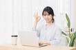 © garage38 - 部屋でノートパソコンを使いながらOKのジェスチャーをする若い女性