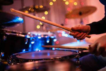 Wall Mural - Close up on hands of unknown caucasian woman with drumsticks - unknown female playing drums at night