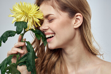 Portrait of a beautiful woman with a yellow flower on a light background charming smile model red hair