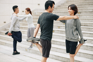 Sticker - Happy young Asian couple leaning on each other when stretching quadriceps after jogging