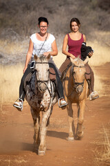 Poster - Two women ride horses along dirt track