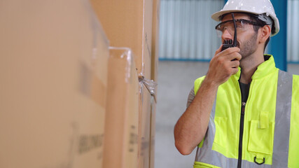 Wall Mural - Professional cargo worker talks on portable radio to contact another worker . Factory and warehouse communication concept .