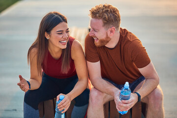 Two young sporty man and woman exercising in urban park.