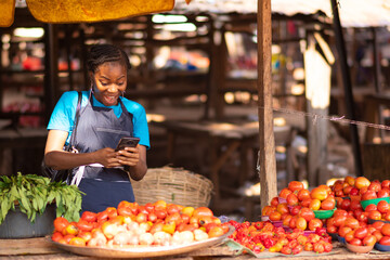 excited nigerian market woman feeling excited while using her phone