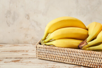 Tray with ripe bananas on light wooden background