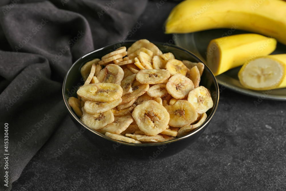 Fresh bananas and crispy chips on dark background