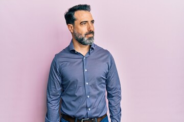 Middle age man with beard and grey hair wearing business clothes smiling looking to the side and staring away thinking.