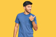 © Krakenimages.com - Young handsome man wearing casual clothes smiling with happy face looking and pointing to the side with thumb up.