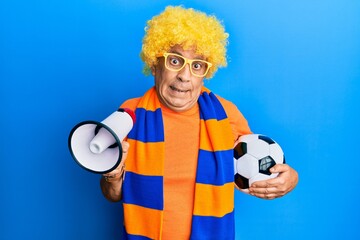 Sticker - Senior hispanic man football hooligan cheering game holding ball and megaphone clueless and confused expression. doubt concept.