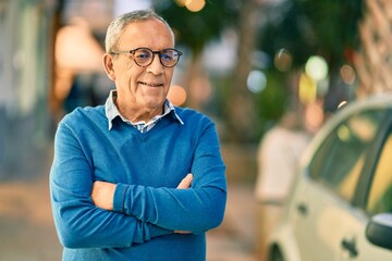 Wall Mural - senior grey-haired man with arms crossed smiling happy standing at the city.