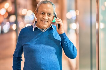 Wall Mural - senior grey-haired man smiling happy talking on the smartphone at the city.