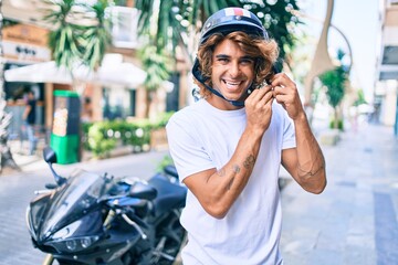 Young hispanic man smiling happy wearing moto helmet over motorcycle at the city