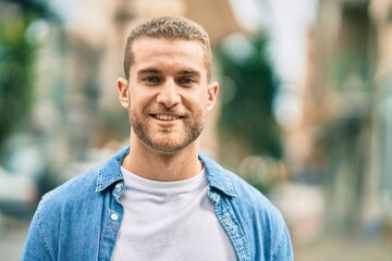 Young caucasian man smiling happy standing at the city.