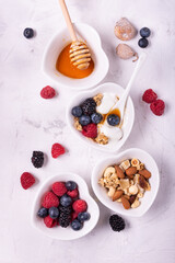 Sticker - heart-shaped white ceramic bowls arranged on a lightly textured background with berries, dried fruit, plain yogurt, wholemeal flakes and honey