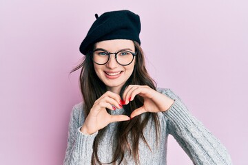 Sticker - Young beautiful caucasian girl wearing french look with beret smiling in love doing heart symbol shape with hands. romantic concept.