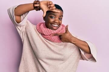 Sticker - Young african american woman wearing winter scarf smiling making frame with hands and fingers with happy face. creativity and photography concept.