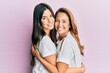 © Krakenimages.com - Beautiful hispanic mother and daughter smiling happy hugging over isolated pink background.