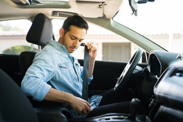 Male driver behind the wheel putting on his seatbelt