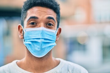 Poster - Young african american man wearing medical mask standing at the city.