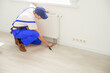 © Angelov - Man in work overalls using wrench while installing heating radiator in room. Young plumber installing heating system in apartment. Concept of radiator installation, plumbing works and home renovation
