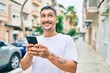 © Krakenimages.com - Young hispanic man smiling happy using smartphone at street of city.