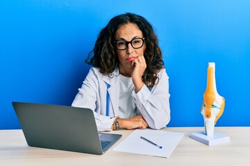 Poster - Beautiful middle age woman doctor at orthopedic clinic thinking looking tired and bored with depression problems with crossed arms.