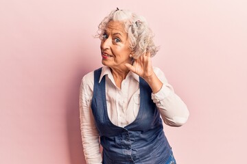 Senior grey-haired woman wearing casual clothes smiling with hand over ear listening and hearing to rumor or gossip. deafness concept.