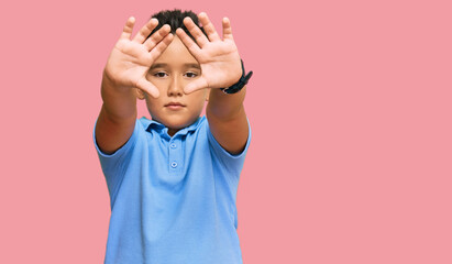 Sticker - Little boy hispanic kid wearing casual clothes doing frame using hands palms and fingers, camera perspective