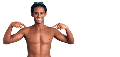 Canvas Print - African handsome man wearing swimsuit and sunglasses looking confident with smile on face, pointing oneself with fingers proud and happy.