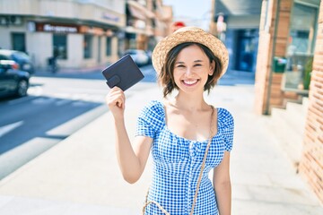 Young beautiful girl smiling happy holding wallet walking at street of city