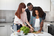 © sofiko14 - Young parents, black man and european woman, teaching their pretty curly daughter cooking and helping chopping vegetables. Family cooking on weekend concept