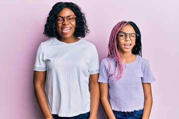 Poster - Beautiful african american mother and daughter wearing casual clothes and glasses winking looking at the camera with sexy expression, cheerful and happy face.