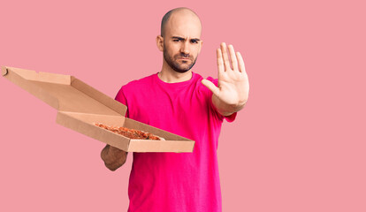 Sticker - Young handsome man holding delivery pizza cardboard box with open hand doing stop sign with serious and confident expression, defense gesture