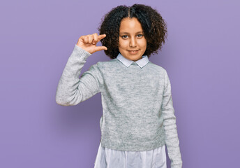 Sticker - Young little girl with afro hair wearing casual clothes smiling and confident gesturing with hand doing small size sign with fingers looking and the camera. measure concept.