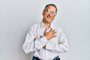 Canvas Print - Middle age indian man wearing casual clothes and glasses smiling with hands on chest with closed eyes and grateful gesture on face. health concept.