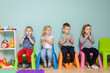 © oksix - Children are sitting on the colorful chairs in the kindergarten