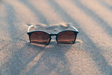 Sun Glasses Lie On A Beach Near The Sea. Sunglasses In The Sand On The Beach. Summer