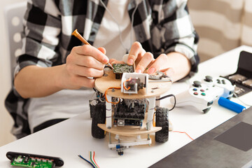Teen hands programming and building science robotics project on his laptop at home during covid-19 pandemic lockdown. STEM education, remote learning, technology concept