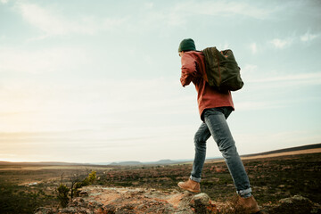 Wall Mural - Caucasian male athlete geared up hiking on mountain during sunrise 