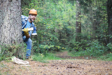 Canvas Print - Male lumberjack in the forest. A professional woodcutter inspects trees for felling.