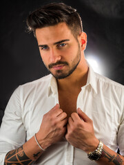 Wall Mural - Half body shot of handsome young man with elegant shirt, looking at camera, on dark background in studio