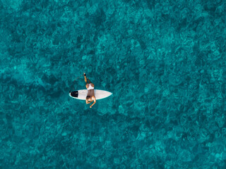 Wall Mural - Surfer woman with surfboard in blue ocean. Aerial view with surfgirl