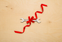 Pliers, Screwdriver, Wrench Tied With A Red Ribbon, Tools On A Wooden Background