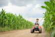 © Jacek - A farmer boy is driving a tractor through a corn field.