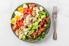 Healthy Cobb Salad With Chicken, Avocado, Bacon, Blue Cheese, Tomato And Eggs With Fork. Keto Diet Food. Top View