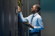 © Seventyfour - Graphic side view portrait of African American network engineer connecting cables in server cabinet while working with supercomputer in data center, copy space